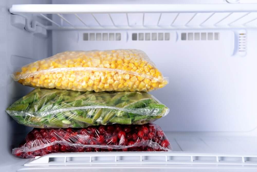 Frozen berries and vegetables in bags in freezer